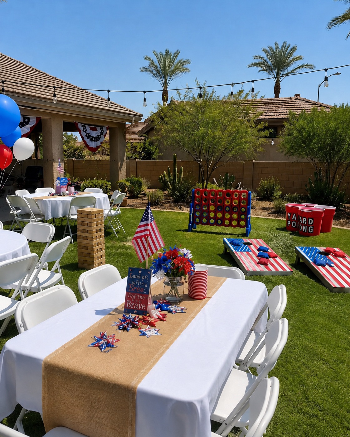 Fourth of July backyard party setup with tables, white folding chairs, giant yard games, and patriotic decorations